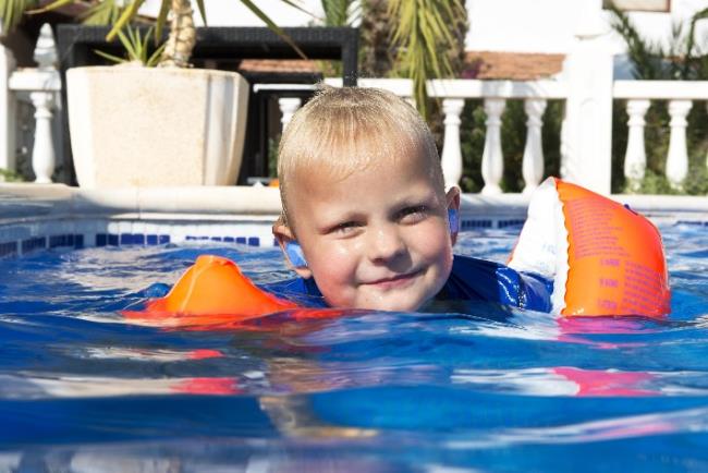 ילד קטן בבריכה עם אטמי אוזניים כדי להימנע מדלקת אוזניים חיצונית